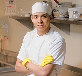 person smiling while wearing a cook uniform