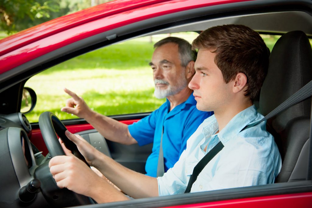 teen boy learning how to drive by an adult