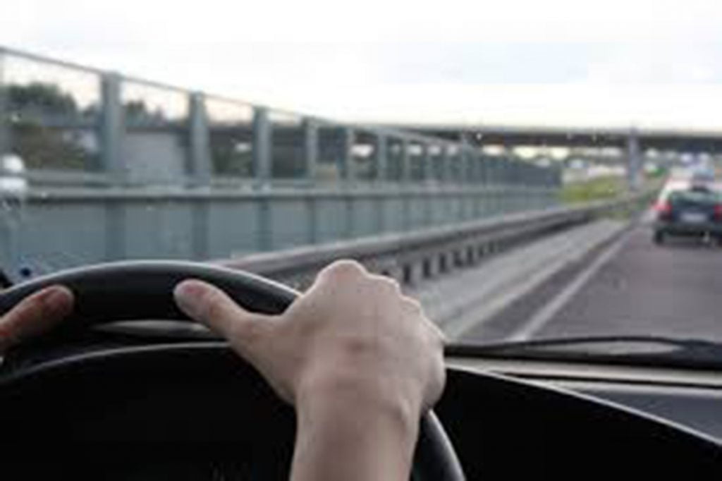 hands on a steering heel driving a car