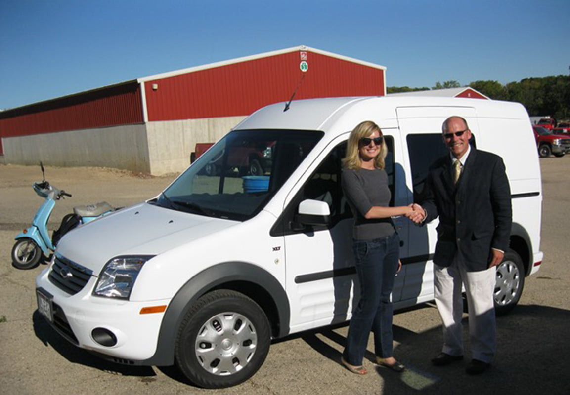 man and woman shaking hands by a white van