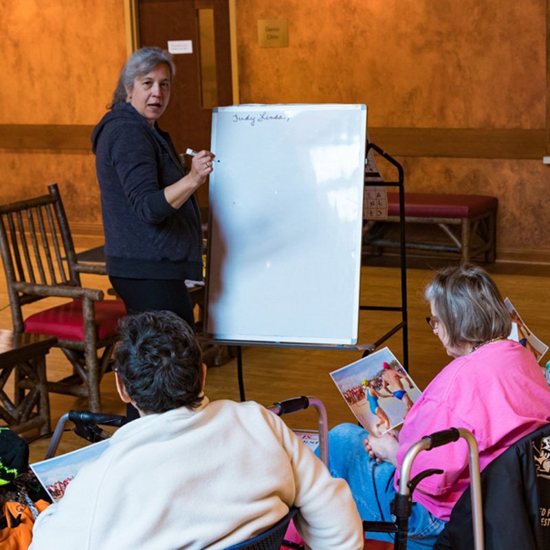 Woman teaching older adults a lesson with using a whiteboard