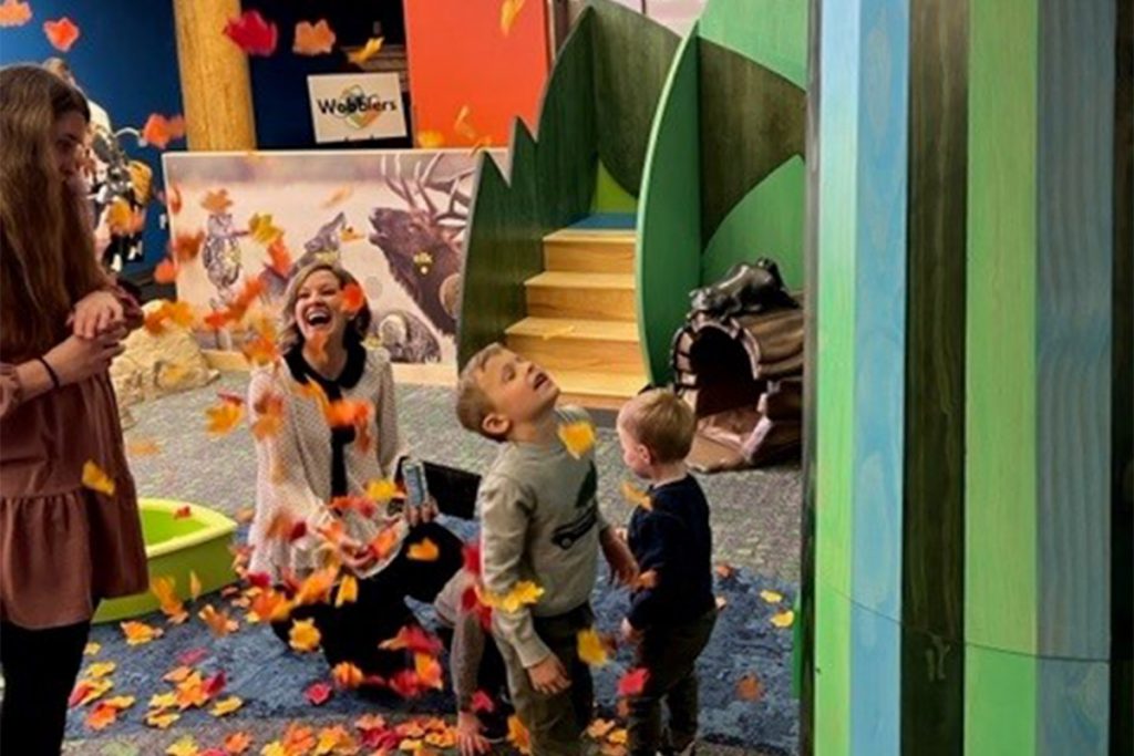 children playing with fake leaves with parents